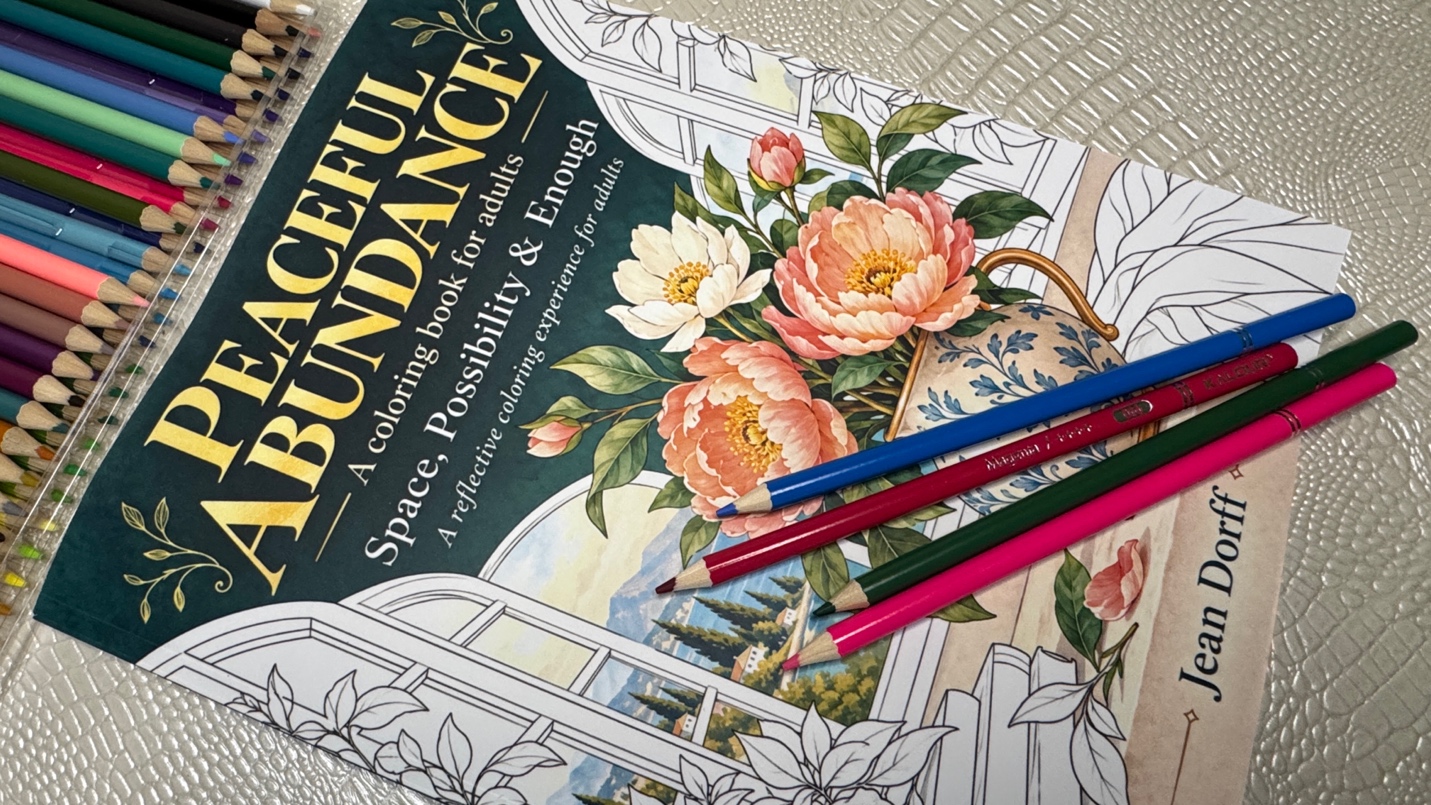 Peaceful Abundance adult coloring book by Jean Dorff with colored pencils across the partially colored floral cover.